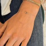 Hand wearing gold bracelets with red nail polish on a blurred background