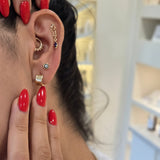 Close-up of a person's ear with earrings and hands with red nail polish.