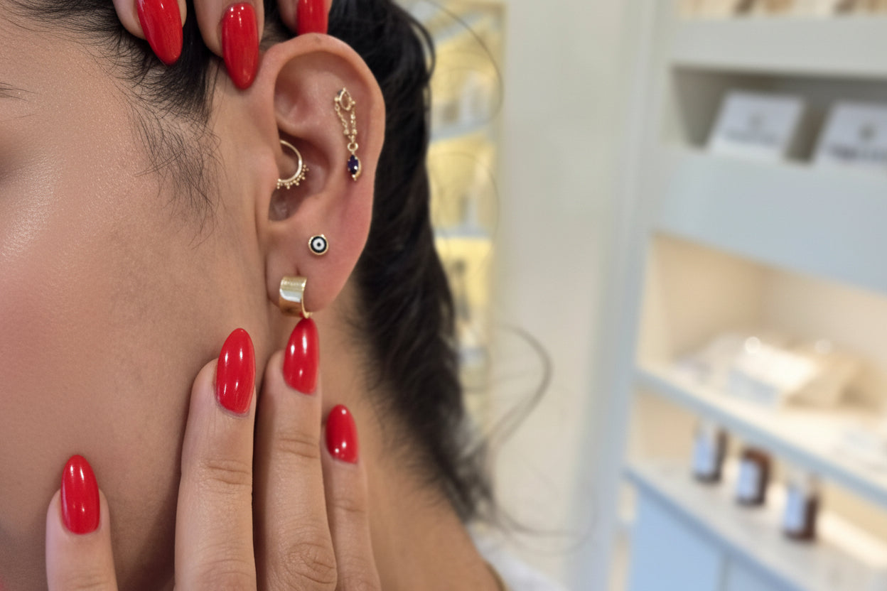 Close-up of a person's ear with earrings and hands with red nail polish.