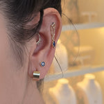 Close-up of an ear with multiple earrings and a blurred background