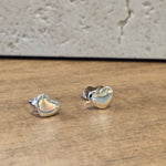 Heart-shaped silver earrings on a wooden surface