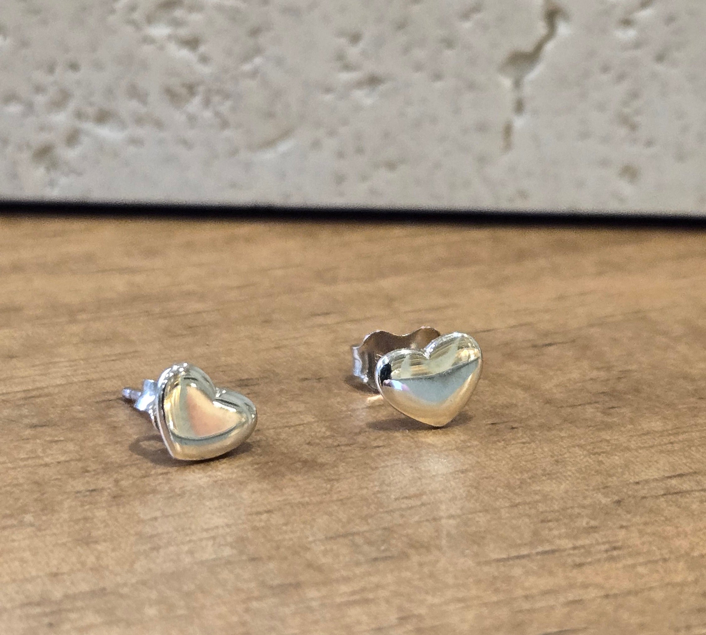 Heart-shaped silver earrings on a wooden surface