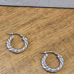 Gold twisted hoop earrings on a wooden surface