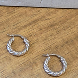 Gold twisted hoop earrings on a wooden surface
