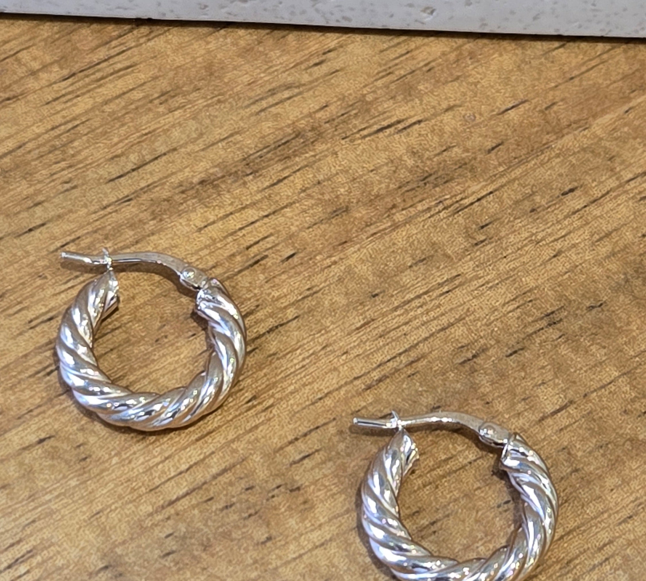 Gold twisted hoop earrings on a wooden surface