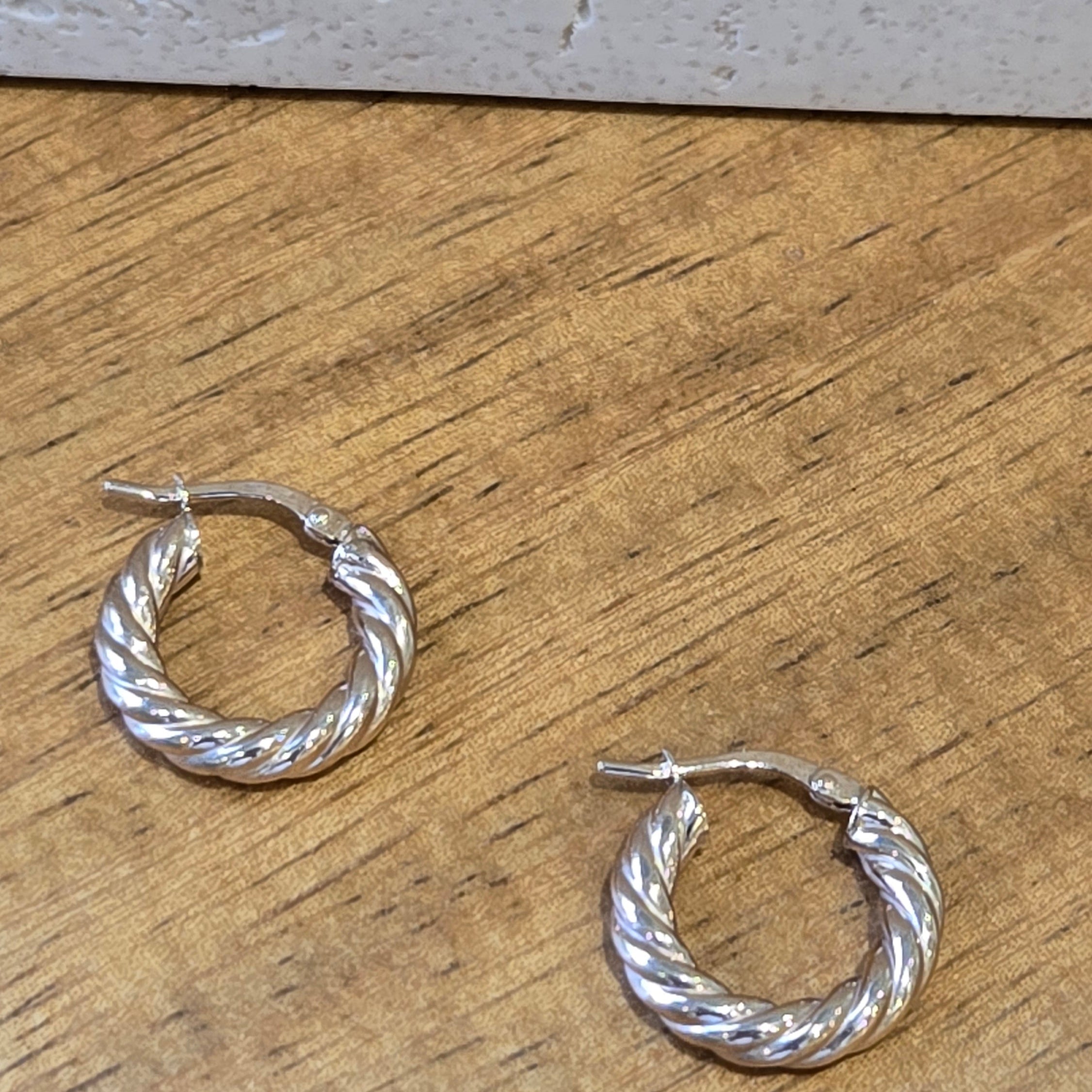 Gold twisted hoop earrings on a wooden surface