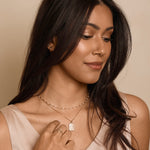 Woman wearing a necklace with a heart pendant against a beige background
