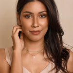 Woman wearing a necklace with a beige background