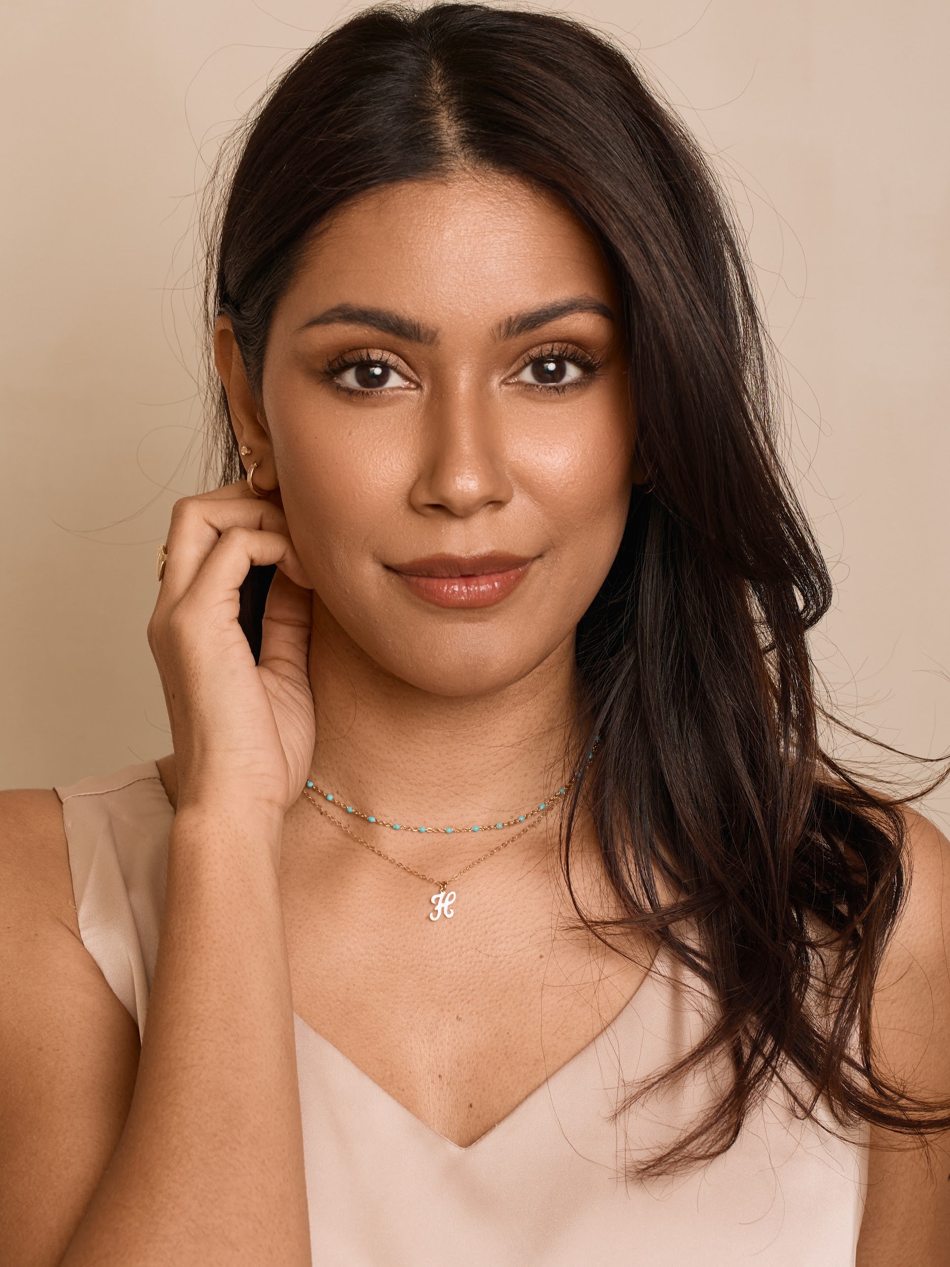 Woman wearing a necklace with a beige background