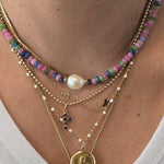 Close-up of layered gold necklaces with coins and beads on a white background