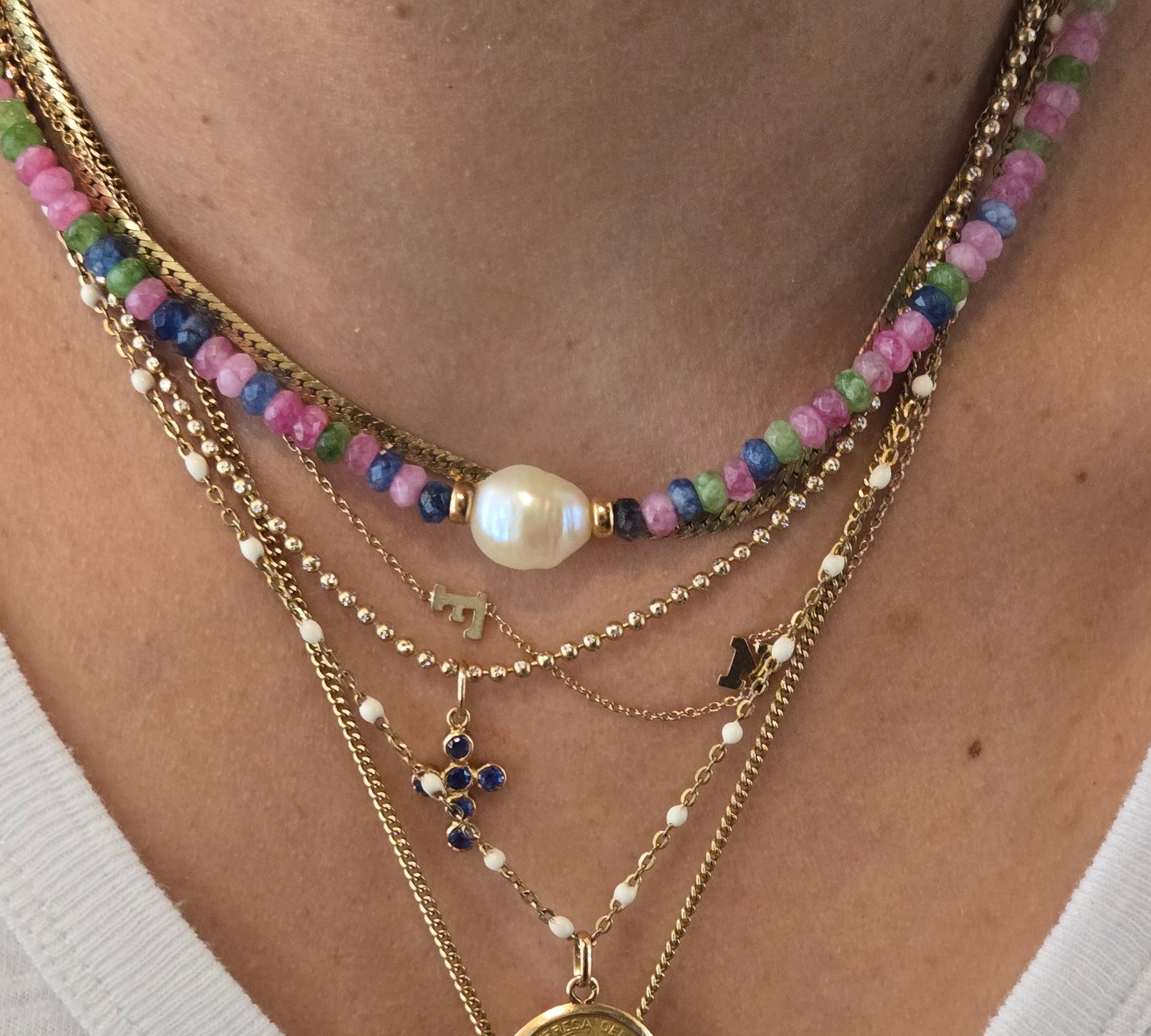 Close-up of layered gold necklaces with coins and beads on a white background