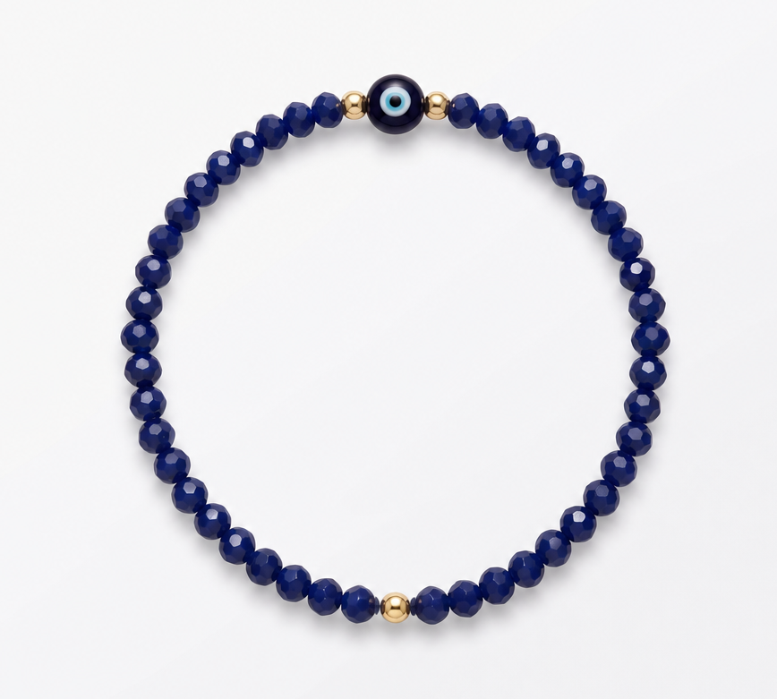 A beaded stretch bracelet featuring deep navy blue faceted beads, accented with small gold spacer beads and a central evil eye charm, displayed on a clean white background.