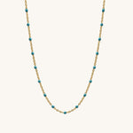 Necklace with gold chain and turquoise beads on a white background