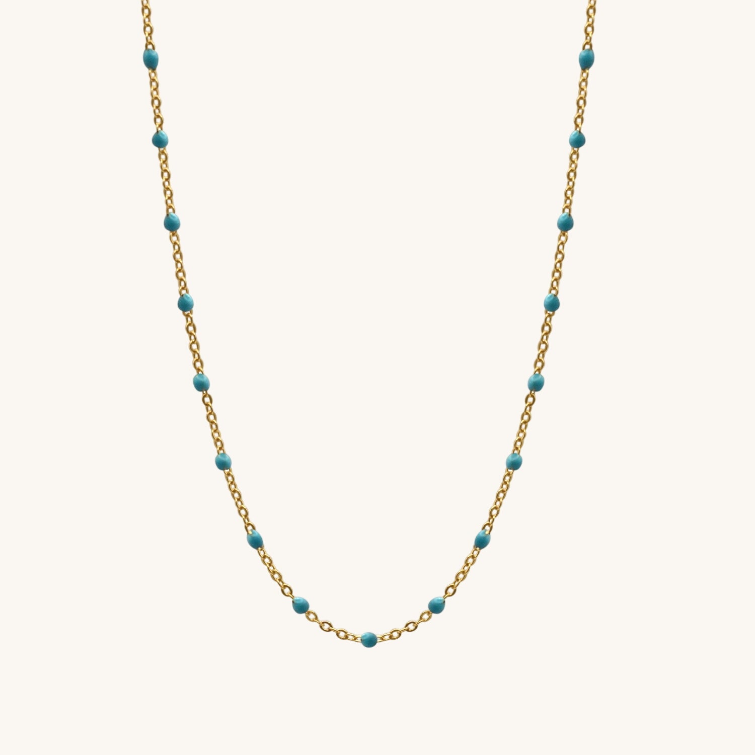 Necklace with gold chain and turquoise beads on a white background