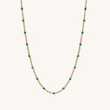 Necklace with gold chain and turquoise beads on a white background