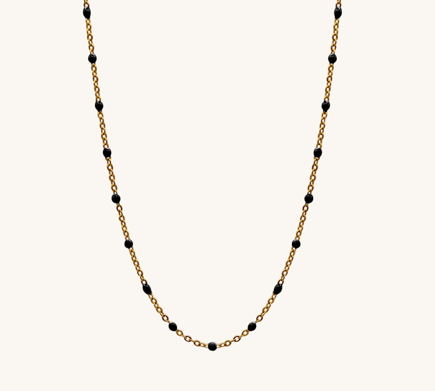 Gold chain necklace with black beads on a white background
