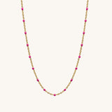 Necklace with gold chain and pink beads on a white background